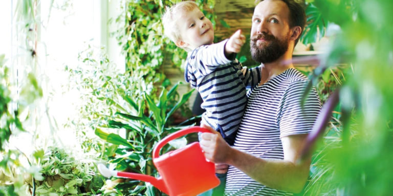 Vater mit Sohn gießt Pflanzen